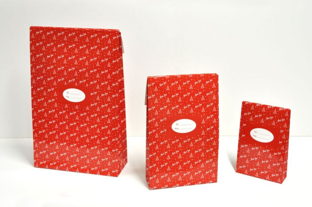 Festlig gavepose med limstripe, perfekt for julegaveinnpakning. Laget av papir i julemotiv, tilbyr denne posen både stil og praktisk lukking for en perfekt gave.